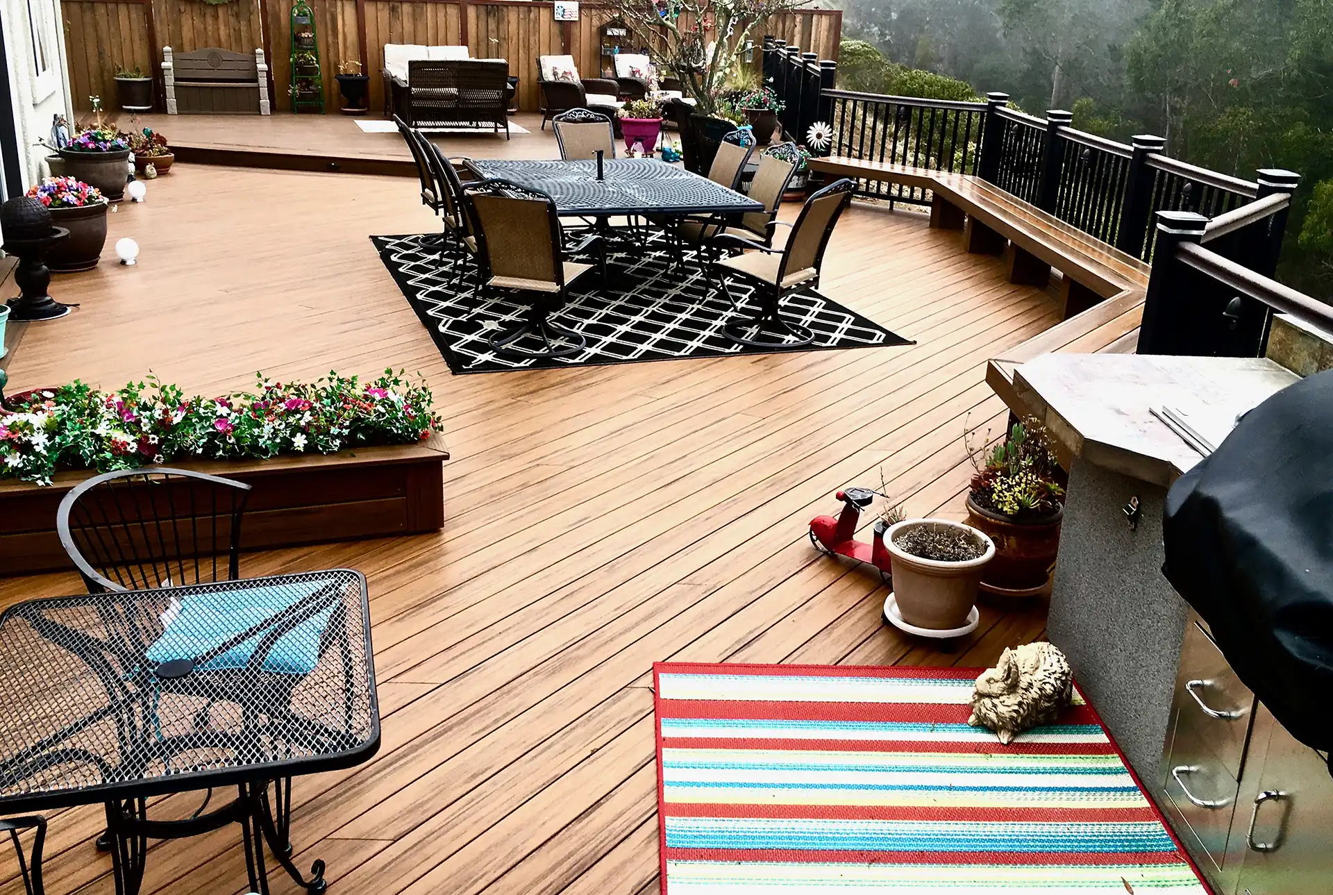 photo of a custom deck made with composite materials with outdoor furniture, an outdoor kitchen, built-in seating, and deck railing - Custom deck builders near me San Francisco Bay