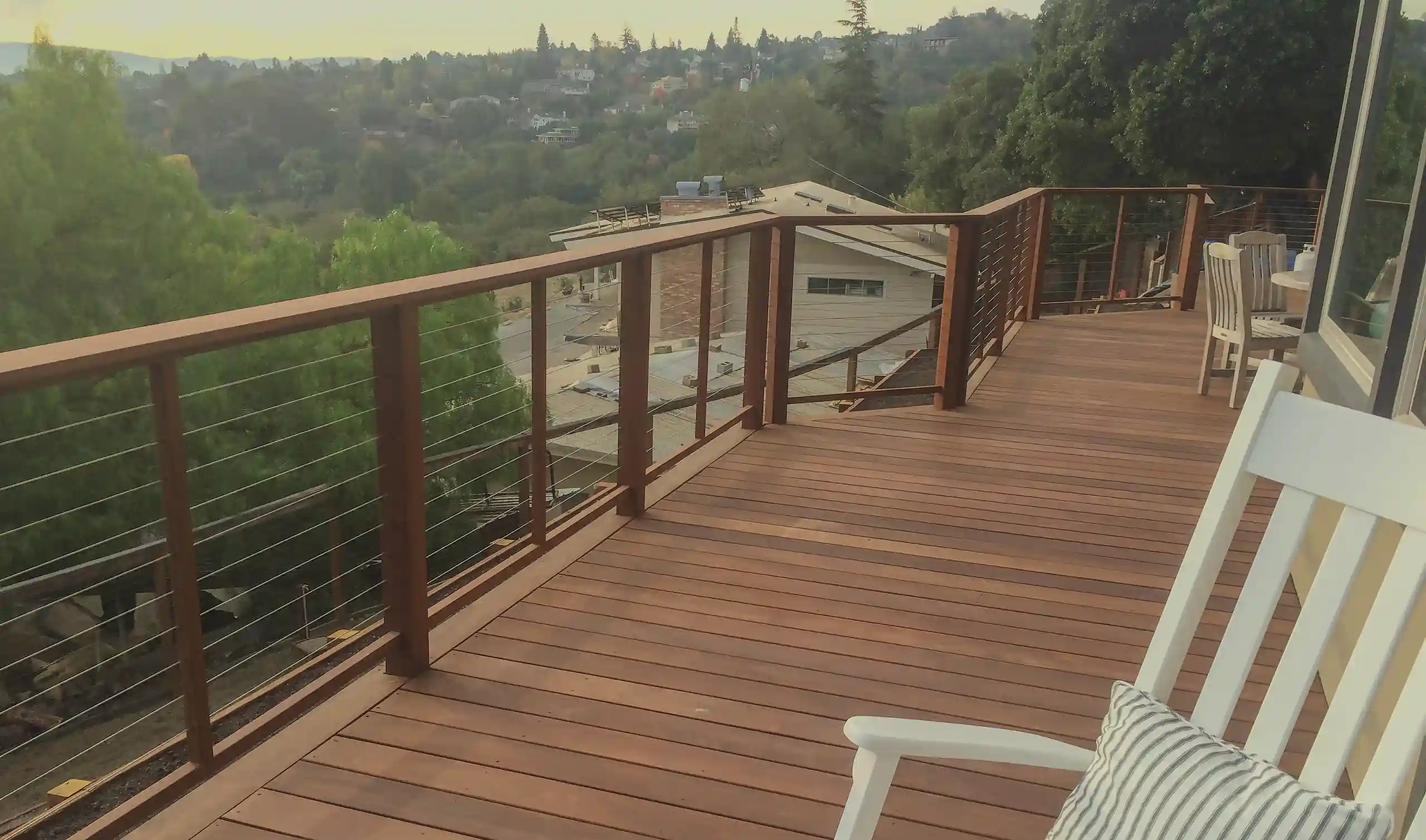 photo of an elevated deck with cable railing and a white rocking chair - Custom Decks Builder in Belmont CA