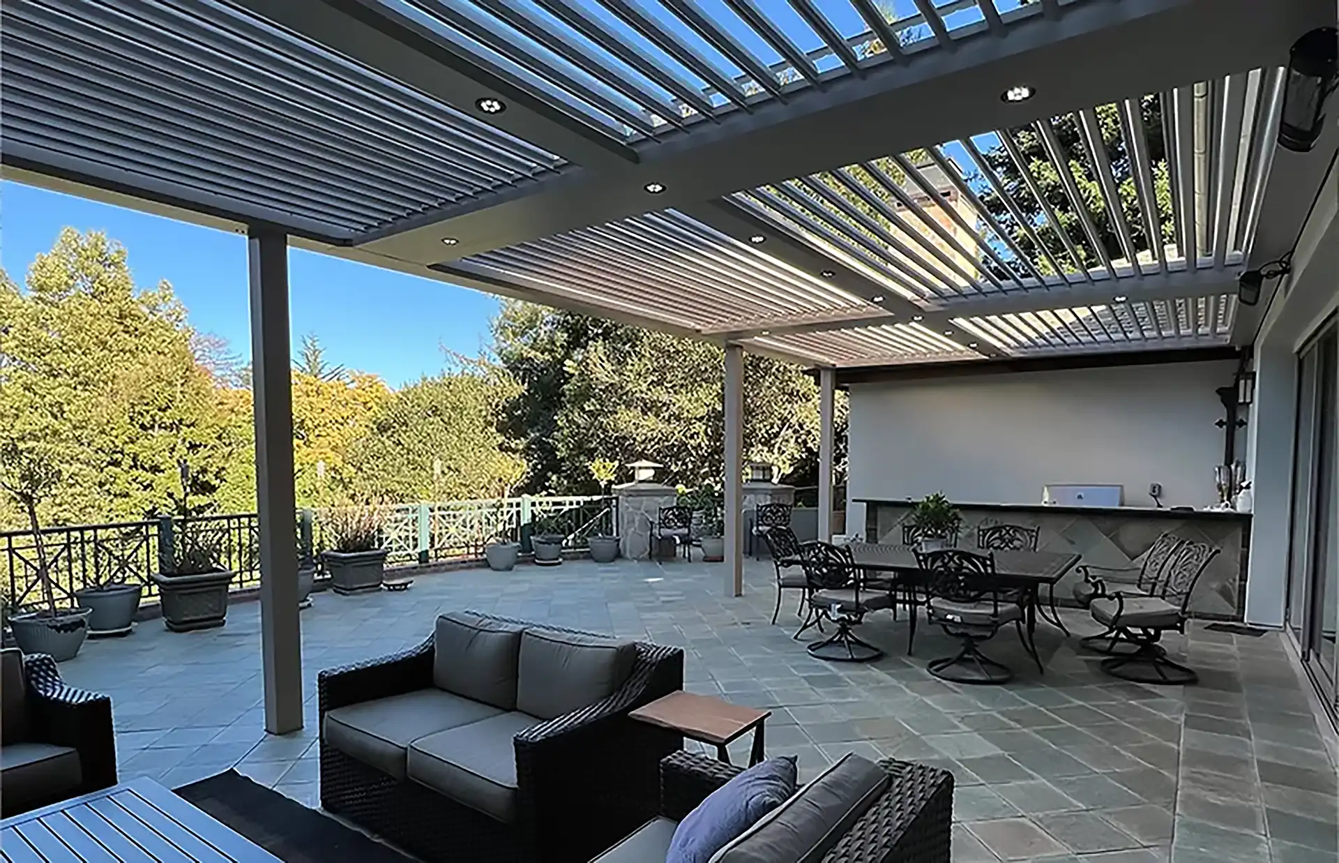 photo of a patio with stone pavers, outdoor furniture, and a louvered pergola - Patio builders and Patio Covers Contractor in San Francisco Bay